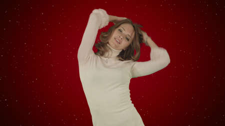Beautiful woman dances on red background with snowの写真素材
