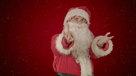 Santa Claus dancing in costume on red background with snowの写真素材