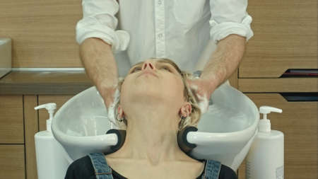 Hair stylist at work - hairdresser washing hair to the customer before doing hairstyleの写真素材