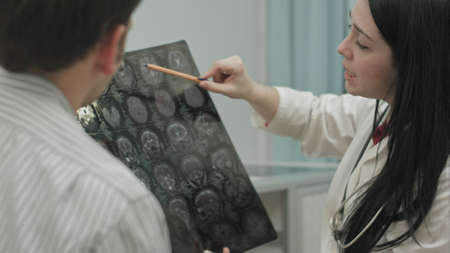 Female doctor in clinic show x-rays to male patient.の写真素材