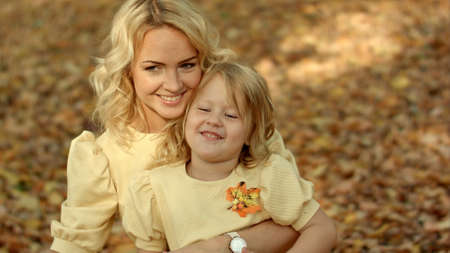 Happy mother with her daughter in autumn parkの写真素材