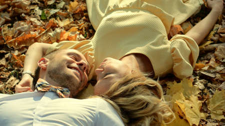Smiling couple lying in autumn parkの写真素材
