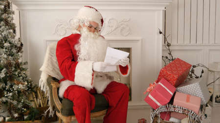 Santa Claus opening an envelope and reading a letterの写真素材