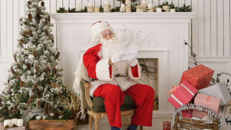 Santa Claus sitting in his workshop reading a letterの写真素材