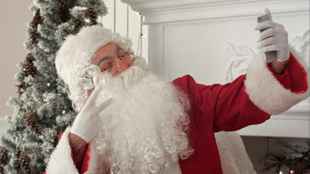 Santa Claus using mobile phone to take Xmas selfiesの写真素材