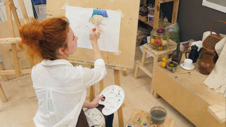 Concentrated woman artist painting pumpkin still life with watercolorsの写真素材