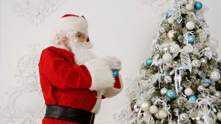 Santa Claus decorating Christmas tree with baublesの写真素材