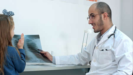 Little girl playing with xray image held by smiling male doctorの写真素材