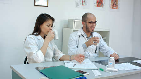 Medical personnel chatting while having coffee breakの写真素材