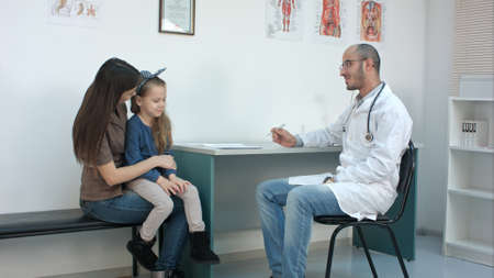 Pediatrician doctor examining child, while mother holding babygirl in her armsの写真素材