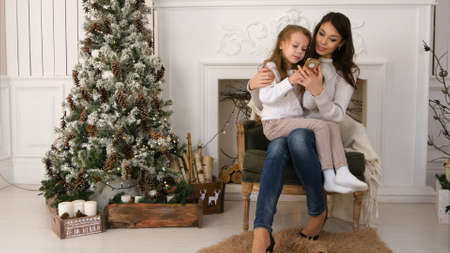 Mother showing her little daughter how to type a message to Santa on the phoneの写真素材