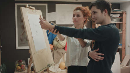 Female painter teaching young man how to draw classical faceの写真素材