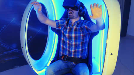 Excited young man enjoying virtual reality attraction in a vr chairの写真素材