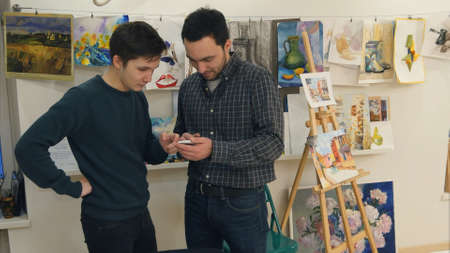 Two young men using smartphone in art classの写真素材