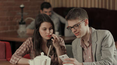 Young couple smoking hookah and use smartphoneの写真素材