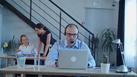 Confident male telemarketer during phone call at workの写真素材