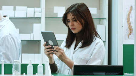 Female pharmacist with digital tablet searching for medicationの写真素材