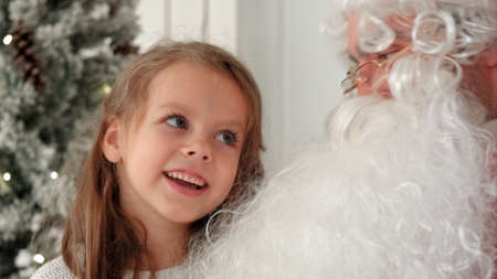 Cute little girl singing Christmas song together with Santa Clausの写真素材