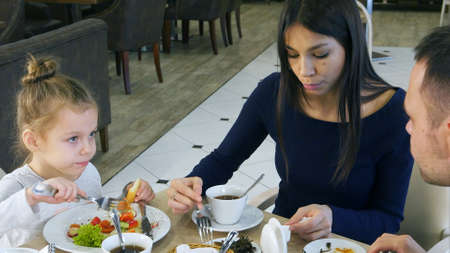 Happy family with daughter having lunch in a cafeの写真素材