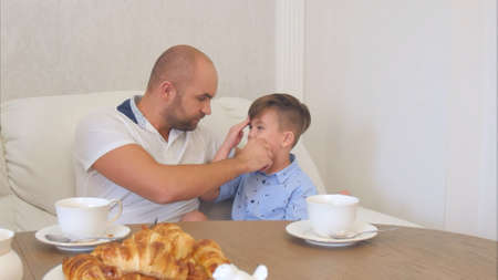 Young father cleaning his little son face after lunchの写真素材