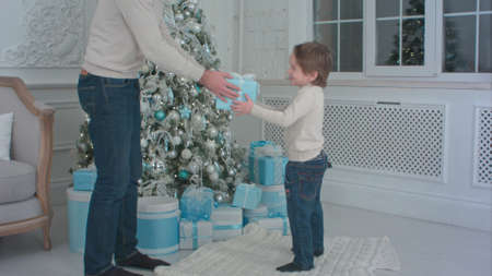 Father and his happy son choosing Christmas presents to openの写真素材