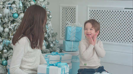 Happy young mother with cute little son playing around with Christmas presentsの写真素材