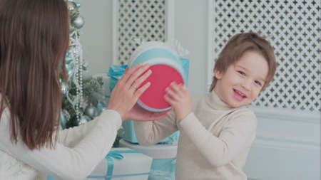 Mother and happy son checking gifts sitting near the Christmas treeの写真素材