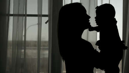 Silhouette of mother throwing baby upの写真素材