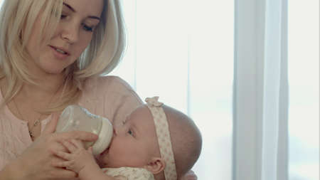 happy mother feeds the baby bottleの写真素材