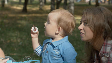 Happy mother and son in the park blowing soap bubbles outdoor portrait.の写真素材