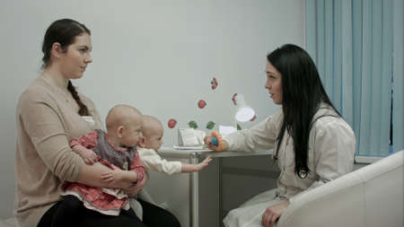 Female pediatrician doctor explain something to mother with newborn twinsの写真素材