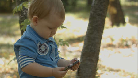 Adorable baby watching cartoon on smartphone in park.の写真素材