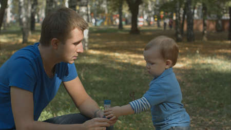 Little baby boy taking bubbles from father and walks away.の写真素材