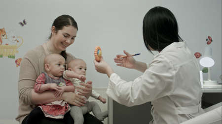 Cute newborn twins being examine by pediatrician with toyの写真素材