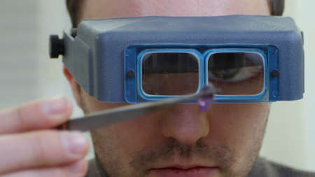 Master jeweler in special glasses looking at gem