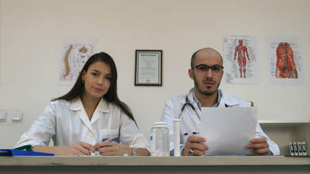 Smiling nurse and male doctor talking to the cameraの写真素材