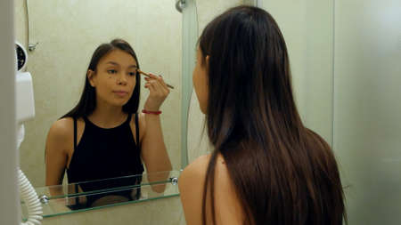 Portrait of young girl applying eyeshadow powder, prepearing for dateの写真素材