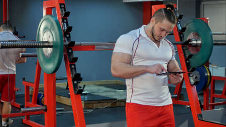 Muscular man using digital tablet during break in the gymの写真素材