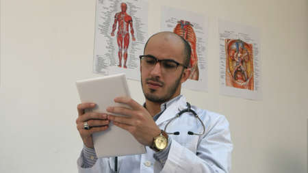 Concentrated male medical worker using digital tabletの写真素材