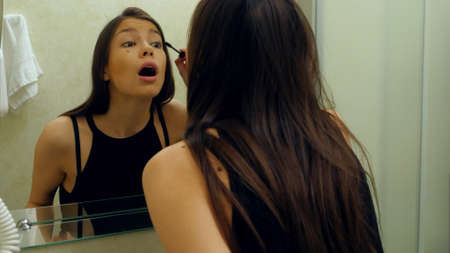 Beauty teenage girl applying mascara make-up very fast because she is lateの写真素材