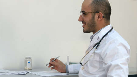 Male pediatrician talking with young mother striking her little girls hairの写真素材