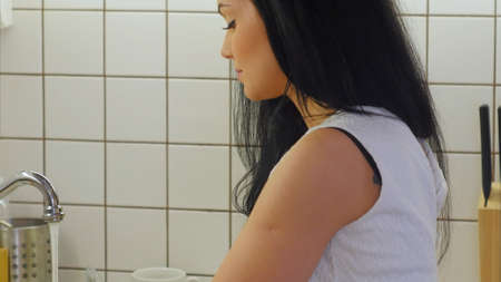 Young woman washing green apple under waterの写真素材