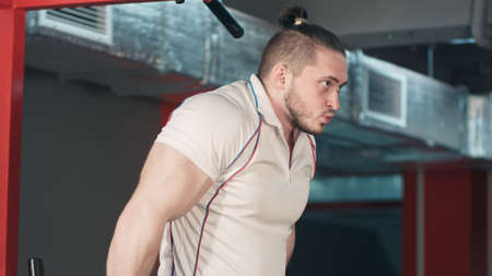Young strong man doing biceps exercises in the gymの写真素材