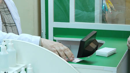 Male customer buy tablet pay with dollars cash at pharmacy counterの写真素材