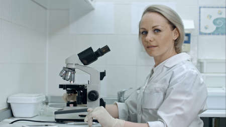 Pretty female with microscope looking at camera in laboratoryの写真素材