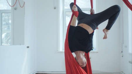 Nice girl flying and doing exercises with aerial silk