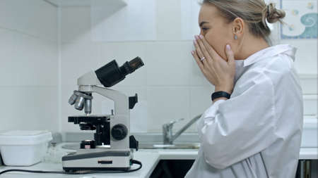 Surprised woman working with a microscope in laboratoryの写真素材