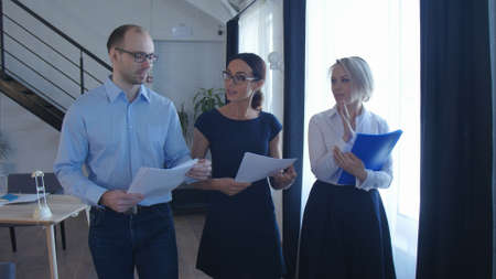 Confident business partners walking down in office building and discussing workの写真素材