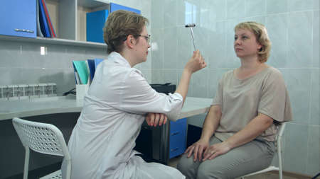 Female neurologist performing neurological tests on a female patient in an officeの写真素材