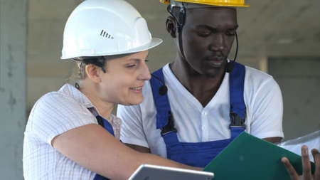 Two workers having conversation and using tablet computerの写真素材